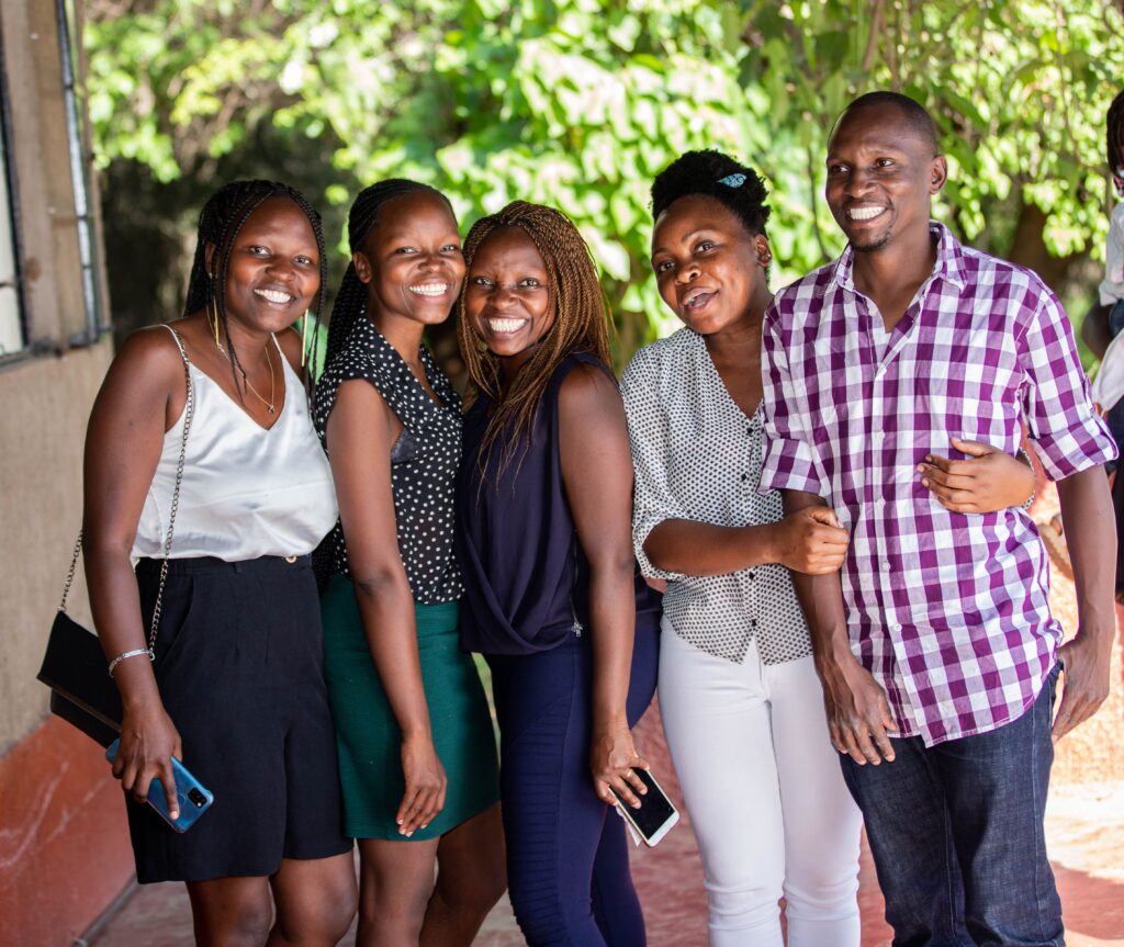 Group of friends joyfully posing together outdoors on a sunny day, exuding happiness and camaraderie.