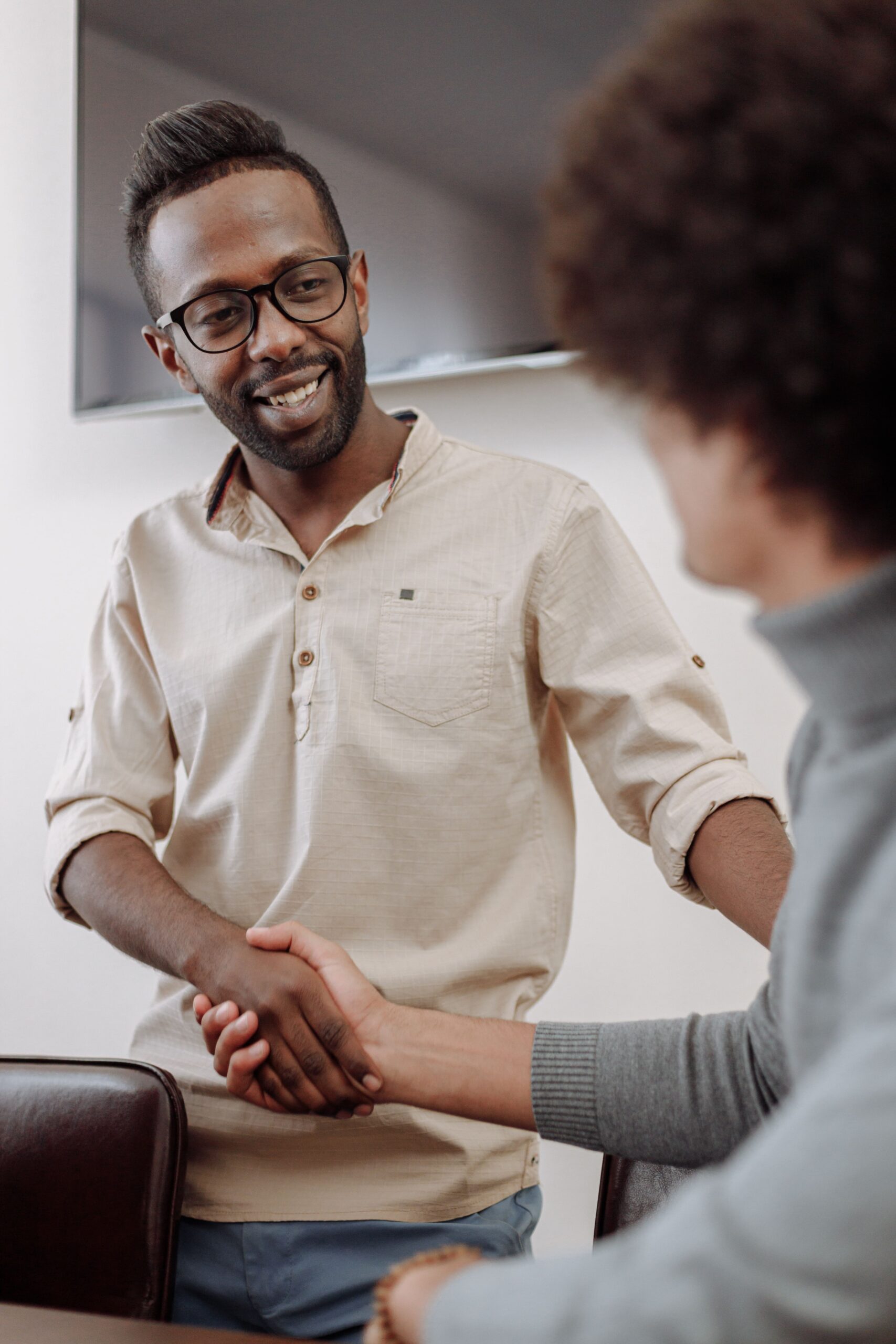 Two men shaking hands in an office, showcasing diversity and cooperation in business.